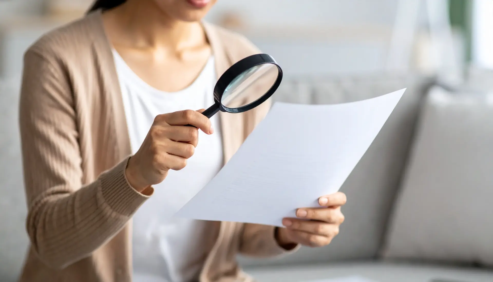 日本の自宅で虫眼鏡を使い書類を慎重に確認する日本人女性