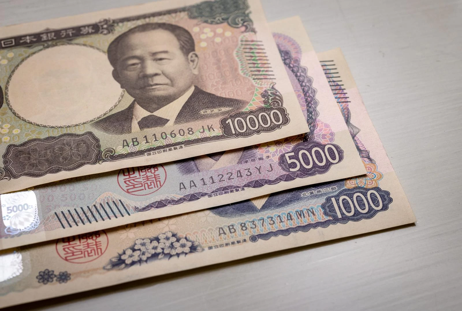 透明なタッチパネルに表示された料金比較グラフを指で操作する人物と日本の紙幣